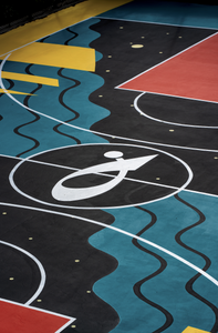 Primo piano delle gradinate del campo da basket ai Giardini Buonvicini, dipinte di giallo e arancione con il logo nero di Cisalfa Sport, partner del progetto.